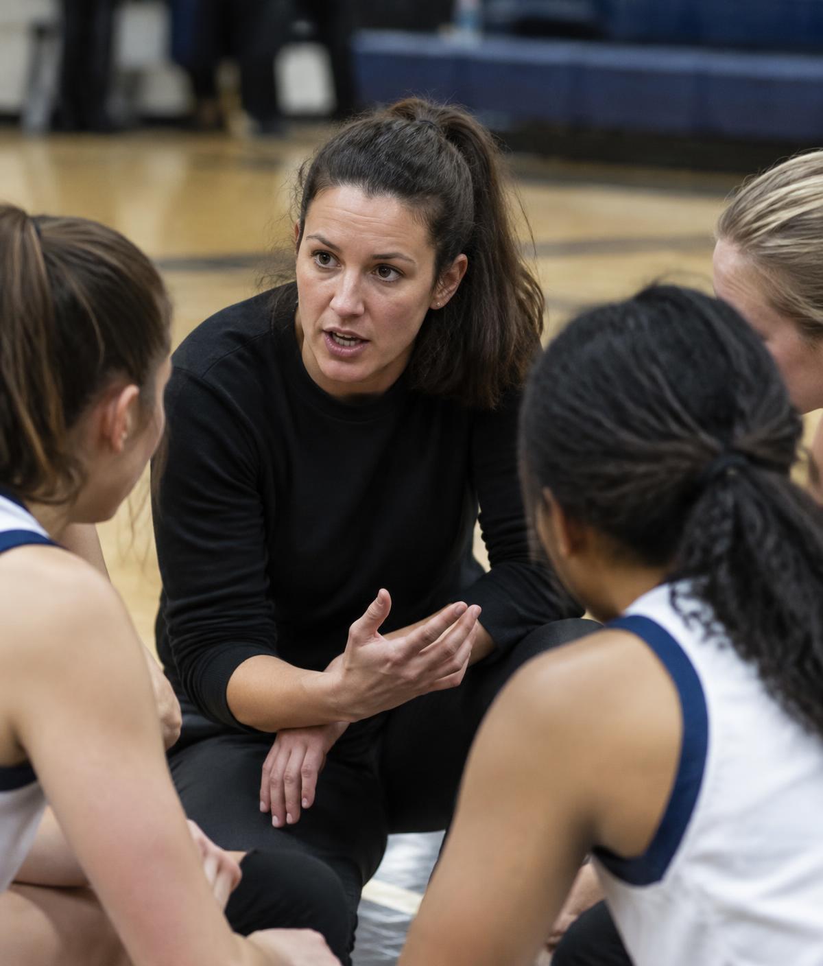 A woman coach speaking with her players in a huddle